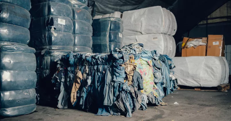 Hög med gamla kläder i fabrikslokal.
