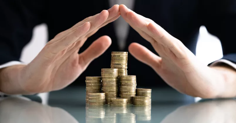 Person håller sina händer över staplar med mynt.