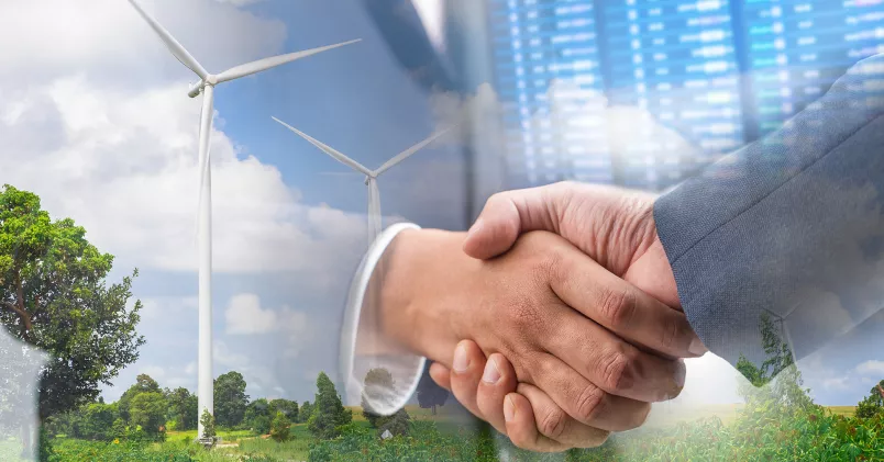 Två personer skakar hand. I bakgrunden syns vindkraftverk, natur och en skärm med siffror.