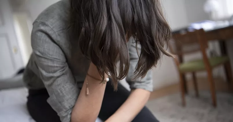 Kvinna sitter ned och håller handen för ansiktet.