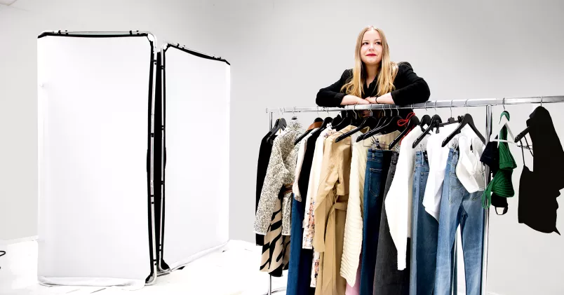 Anna Wanasz står bakom en klädstång med kläder.