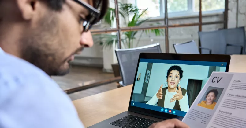 Man intervjuar kvinna i laptop och kollar på hennes cv.