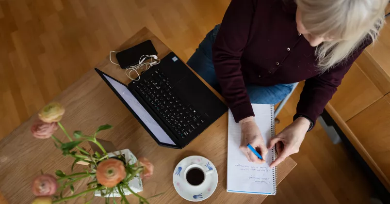 Kvinna sitter och jobbar hemma vid laptop.