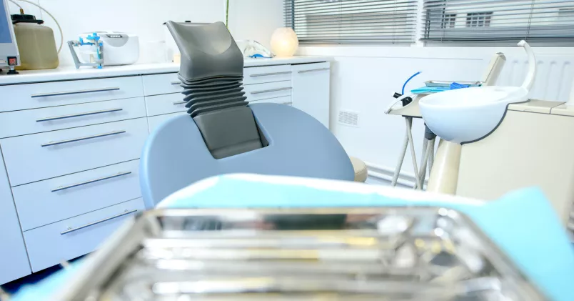 Tom tandläkarstol med tandvårdsinstrument på ett litet bord. 