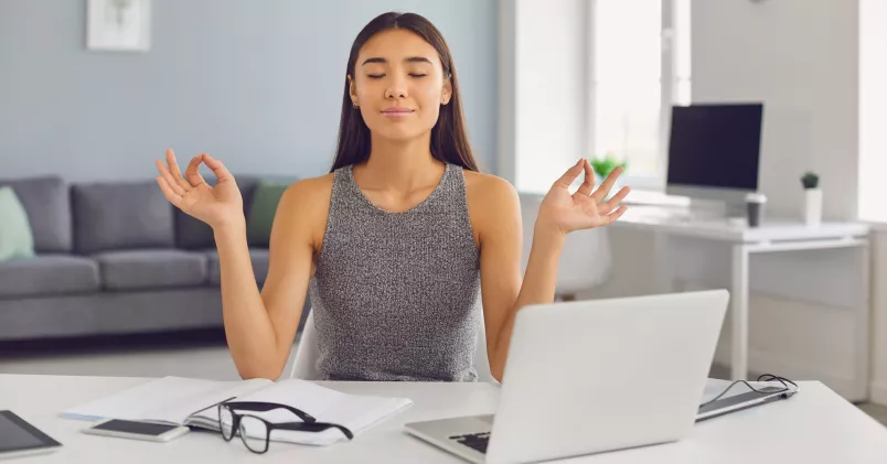 Kvinna gör yoga framför sin dator.