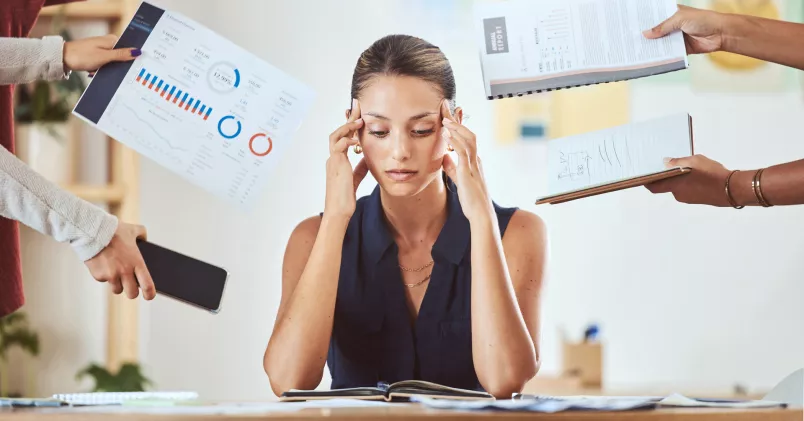 En stressad chef vid sitt skrivbord med huvudet i händerna.