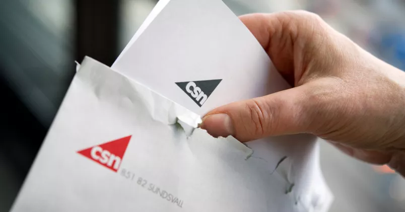 En person öppnar ett kuvert från CSN.