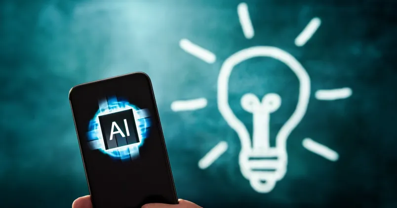 En telefon där skärmen visar AI bredvid en tecknad glödlampa.