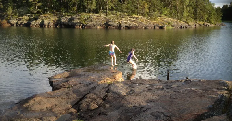 Två flickor  hoppar i vattnet