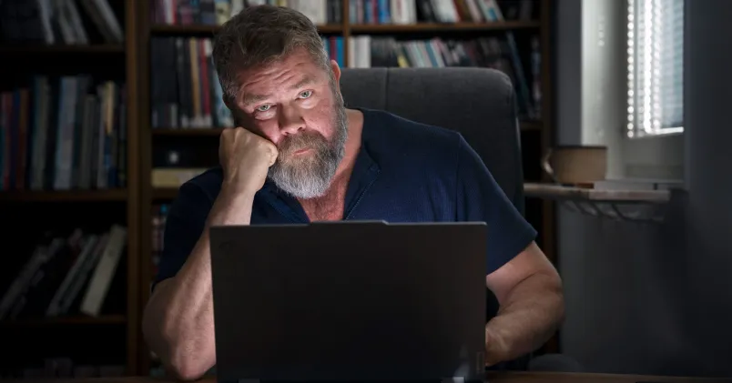 Ghostning vid rekrytering. Jörn Green sökte hundratals jobb utan att få svar. Sitter vid en dator i ett mörkt rum, skäggig, ser allvarlig ut.