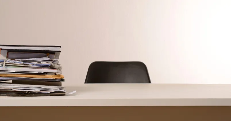 Tillbaka till kontoret. Ett tomt skrivbord på ett ödsligt kontor, fullt med papper. 