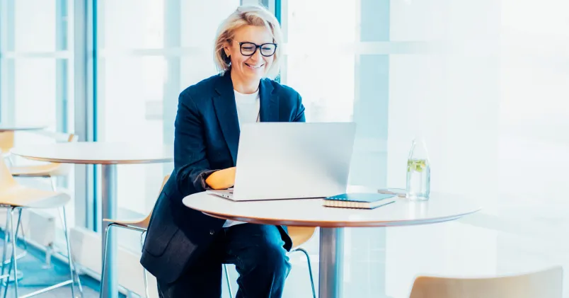 Åldersdiskriminering. På bild en mogen kvinna på kontor, jobbar med bärbar dator.