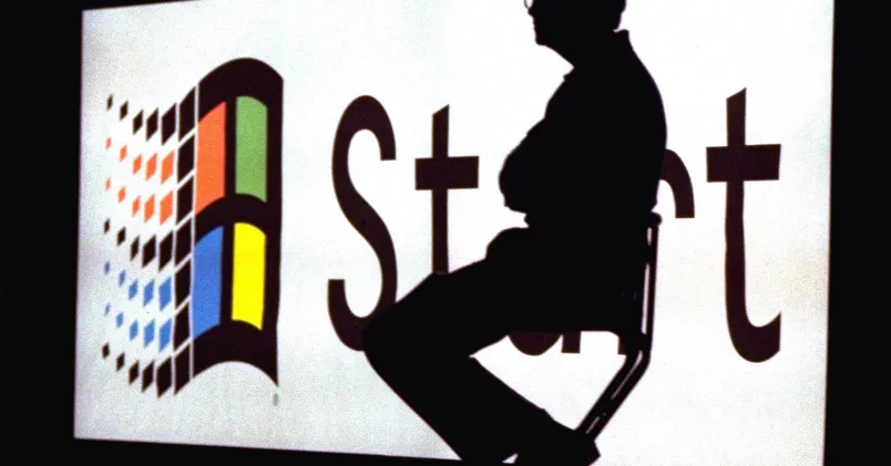 Silhuetten från Microsofts grundare Bill Gates framför en av bolagets gamla logotyper.