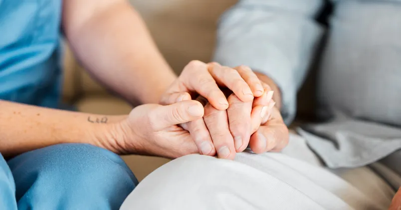 Undersköterska håller en äldre persons hand