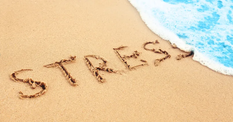 Ordet stress skrivet i sanden