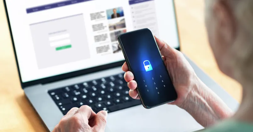 Så undviker du nätfiske efter en dataläcka – expertens varning. PÅ bild en kvinna med bärbar dator och en autentiserigsapp.