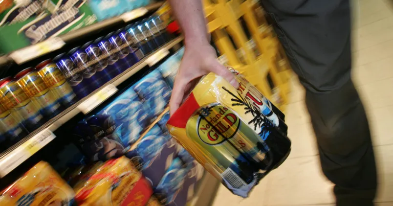 Någon lyfter ett sexpack med ölburkar av märket Norrlands Guld.