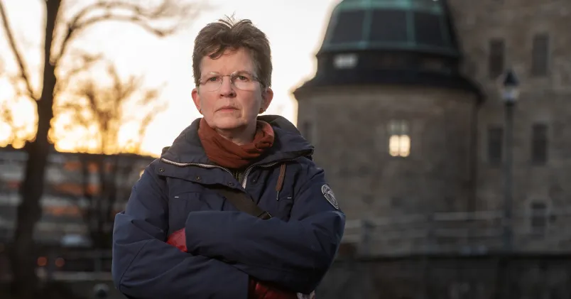 Sif Bjarnason står vid Örebro slott i skymning. Hon ser bestämd ut.