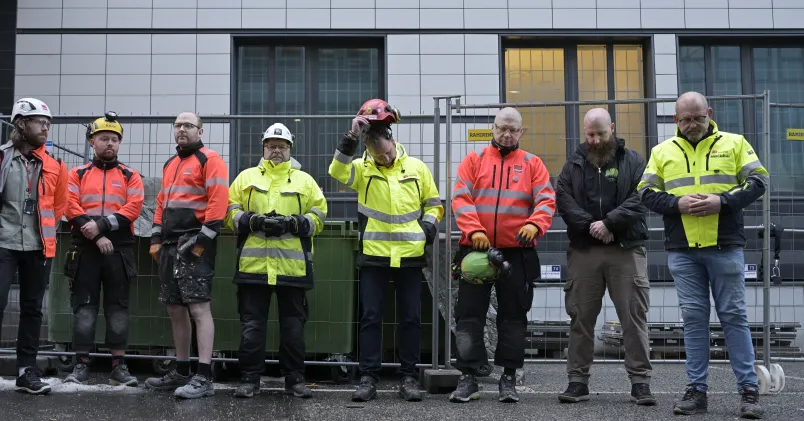 Byggnadsarbetare håller en tyst minut efter hissolyckan i Sundbyberg 2023 där fem arbetare omkom.