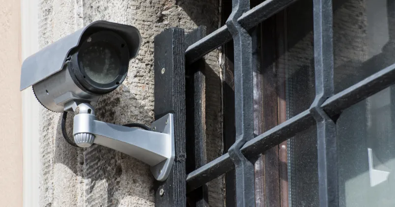 Kamera riktad mot entré på villa, symboliserar polisinsats och husrannsakan.