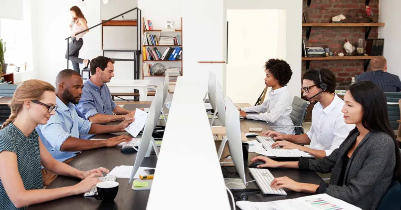 Personer som arbetar i ett öppet kontorslandskap, en kontorstyp som enligt forskning kan öka stress och påverka arbetsmiljön.