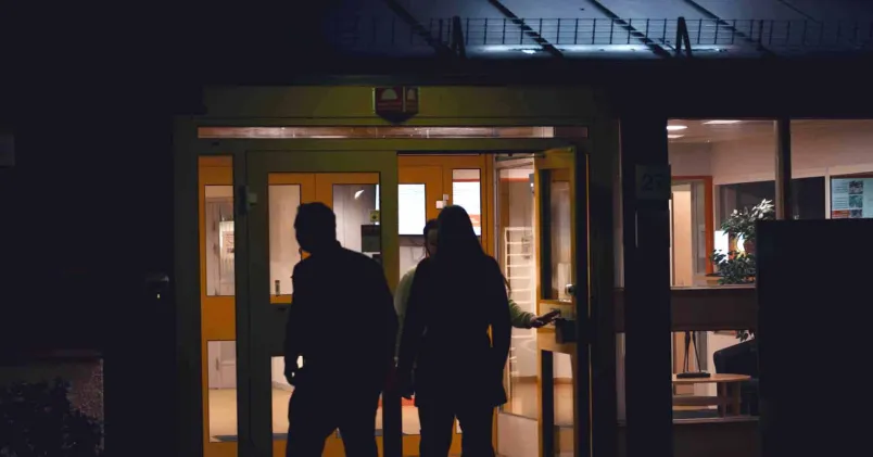 Två personer går in i en upplyst laboratoriebyggnad på kvällen för att arbeta nattskift.