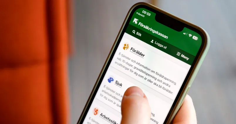 En hand använder Försäkringskassans webbplats på en mobiltelefon. På skärmen visas ingången till information och e-tjänster för föräldrar.