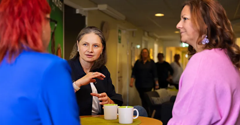 Tre kvinnor som pratar runt fikabordet