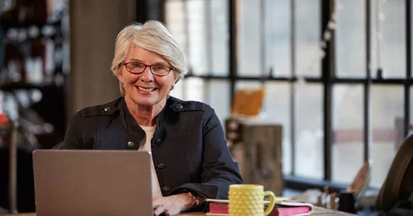 Glad kvinna vid laptop.