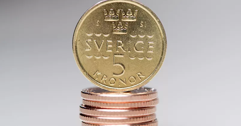 En femkrona balanserar på en stapel med mynt av annan valör.