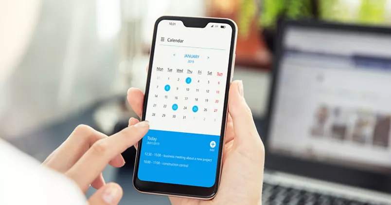 Med en kalenderapp kan du synka mobilen med mejlen och datorn. Kvinna med mobil som visar kalenderapp.