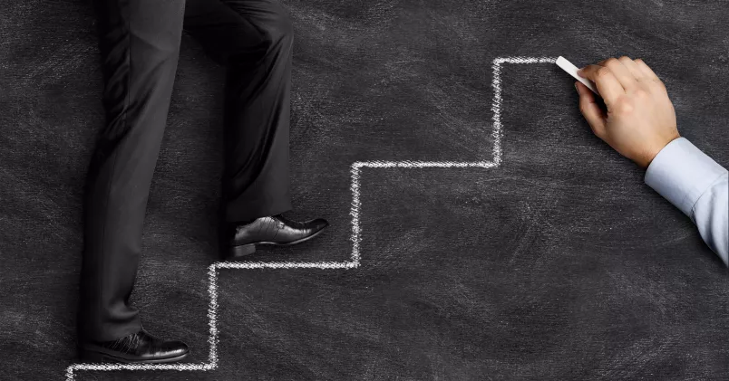 Man går upp för trappa som är ritad på svart tavla.