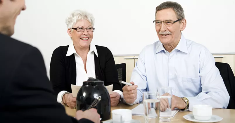 Personer i pensionsålder runt ett fikabord.