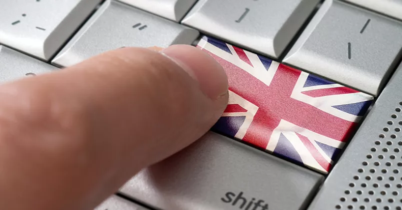 Finger trycker på tangent med brittiska flaggen.