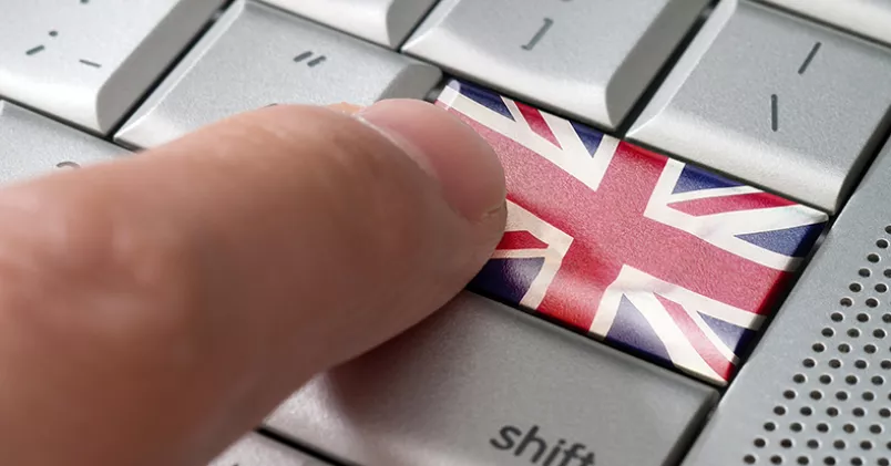Engelska fraser mejl. Finger trycker på tangent med brittiska flaggen.
