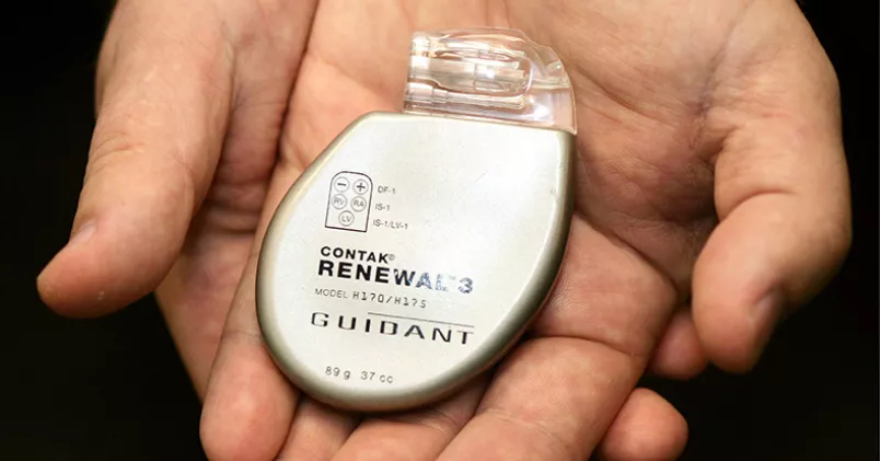 Händer håller upp en pacemaker.