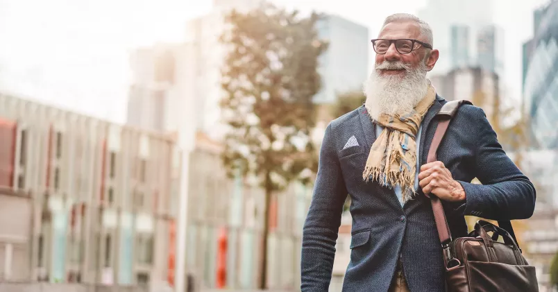 Man i pensionsålder promenerar i stadsmiljö.