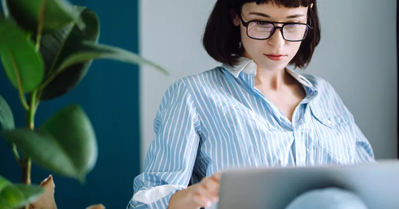 Kvinna sitter med laptop i knät.