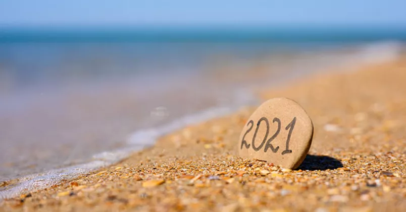 Sten med texten 2021 sticker upp på strand.