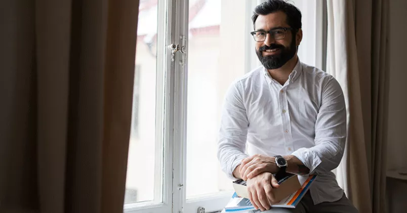 Sebastian Calero undervisar och coachar chefer och företagare i affärsengelska. Sebastian Calero sitter i ett fönster.