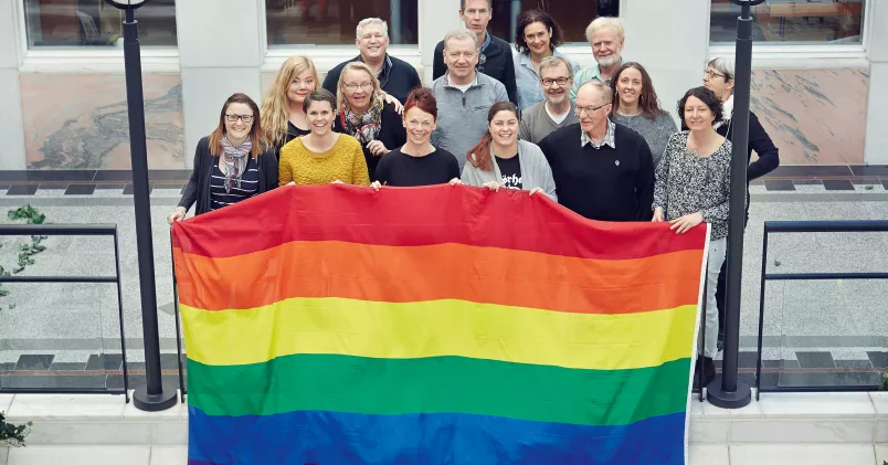 Anställda på Sensus Väst håller upp regnbågsflagga.