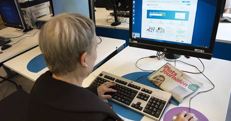Kvinna sitter vid dator och söker jobb på Arbetsförmedlingen.