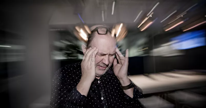 Stress. Stressad man tar sig för tinningarna i snurrig miljö.