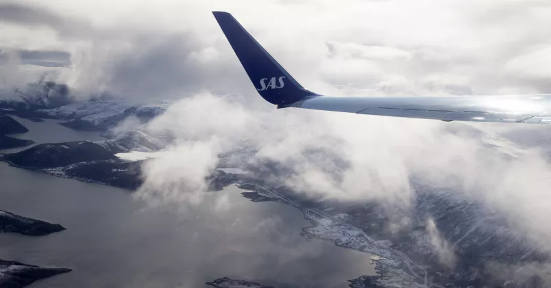 Flygplansvinge med SAS-loggan på plan i luften.