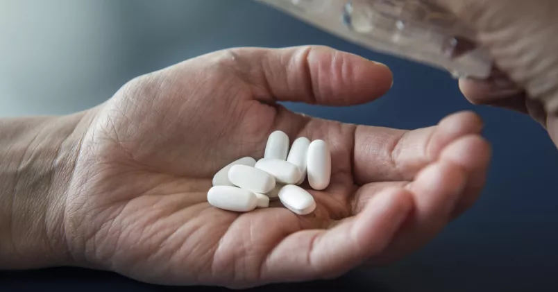 Hand håller upp tabletter.