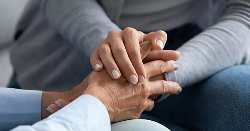 Person håller om annan persons händer.