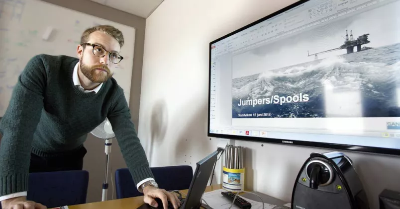 Viktor Stefansson lutar sig över sitt skrivbord och sin laptop.