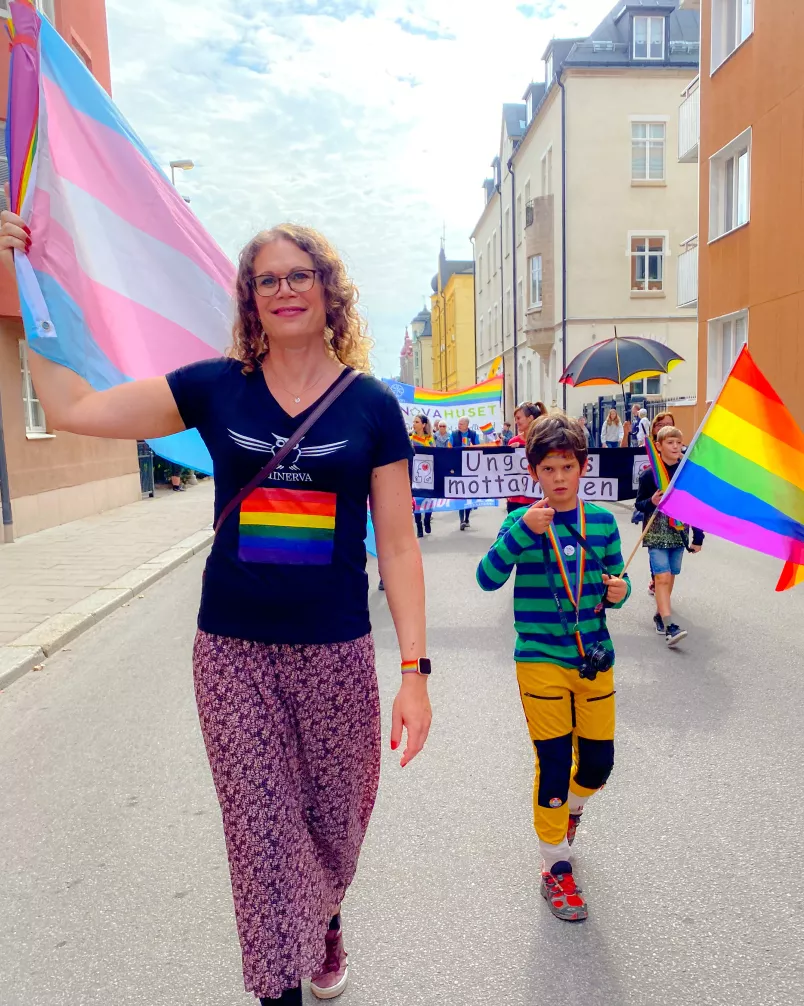 Johanna Gustafsson med en transflagga bredvid sonen som håller i en prideflagga.