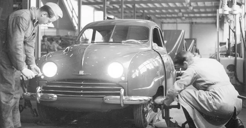 Två anställda fixar hjul och ljuslyktor på en Saab 92, år 1950.