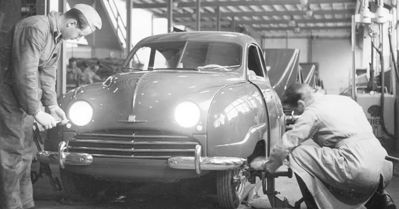 Saab 92, år 1950. Två anställda fixar hjul och ljuslyktor på en Saab 92, år 1950.